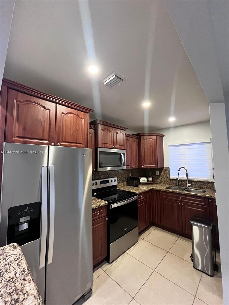 A kitchen features dark wood cabinets, granite countertops, stainless steel appliances, and tile flooring — 4533 SW 143rd Pl, Miami FL 33175, MIAMI, FL