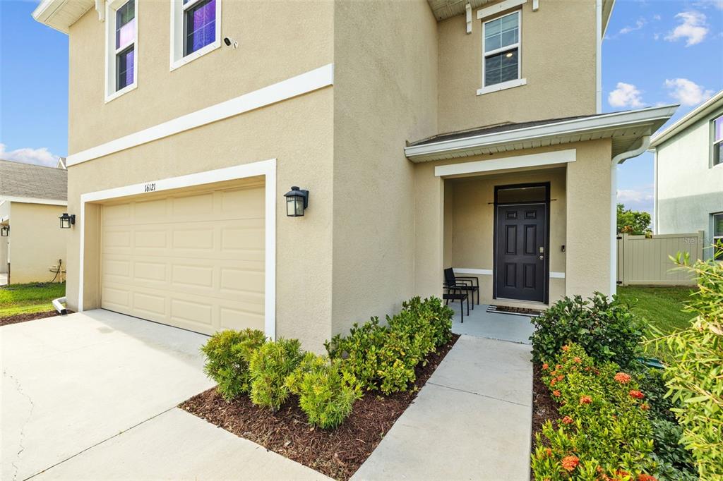 A two-story house exterior features a beige stucco facade, a garage, and a front entrance — 16121 SOFT FERN TRACE, ODESSA, FL