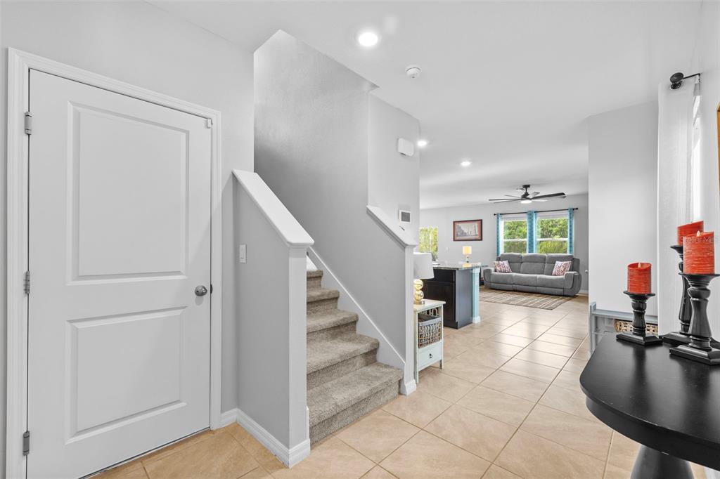 An entryway with tile flooring, a carpeted staircase, and a view into the living room — 16121 SOFT FERN TRACE, ODESSA, FL