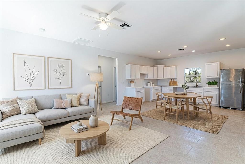 An open-concept living room and kitchen featuring light-colored furniture, tile flooring, and white cabinetry — 1406 BITTERSWEET STREET, LAKE PLACID, FL