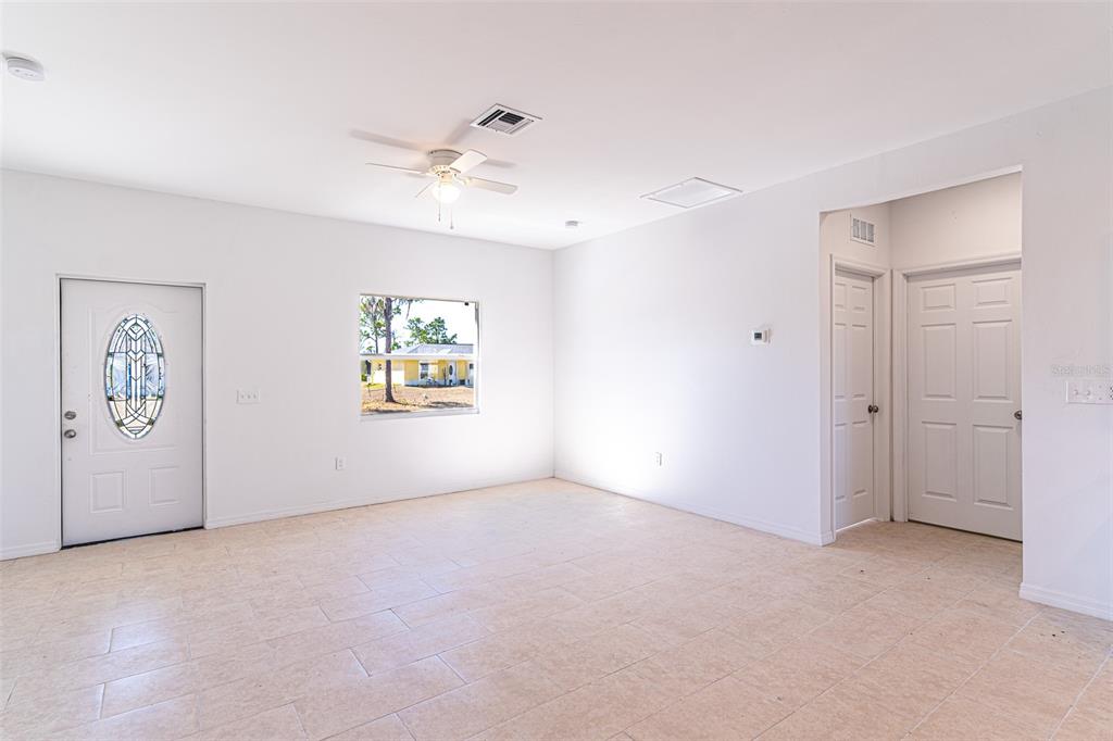 An empty room with white walls, tile flooring, a ceiling fan, and two white doors — 1406 BITTERSWEET STREET, LAKE PLACID, FL