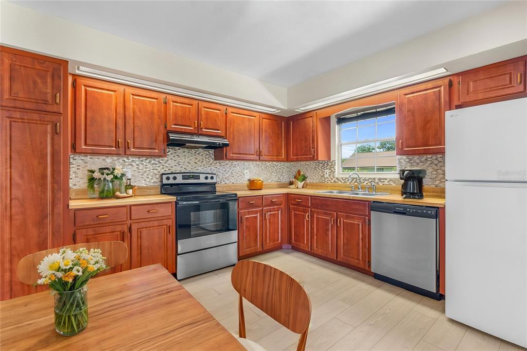 A kitchen with wood cabinets, stainless steel appliances, and a light-colored tile floor — 104 SHOAL CREEK CIRCLE, DAYTONA BEACH, FL