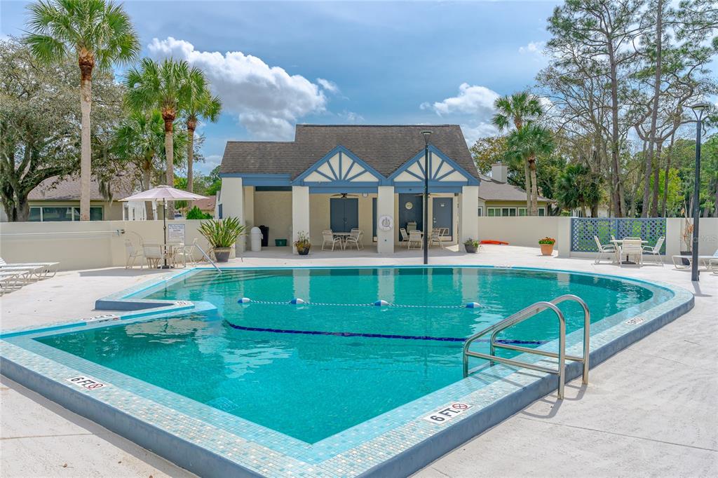 A swimming pool with a tiled edge sits in front of a small community clubhouse — 104 SHOAL CREEK CIRCLE, DAYTONA BEACH, FL