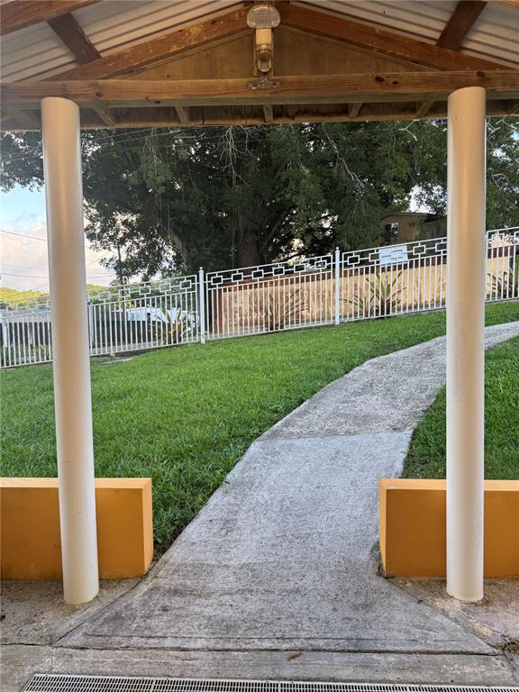A concrete walkway leads through a covered entryway toward a white metal fence and lawn — 17 G23 COLINAS DEL YUNQUE, RIO GRANDE, PR