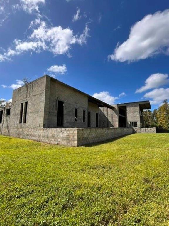 An unfinished concrete block house stands on a grassy lot under a blue sky — 1029 VAN DYKE ROAD, LUTZ, FL