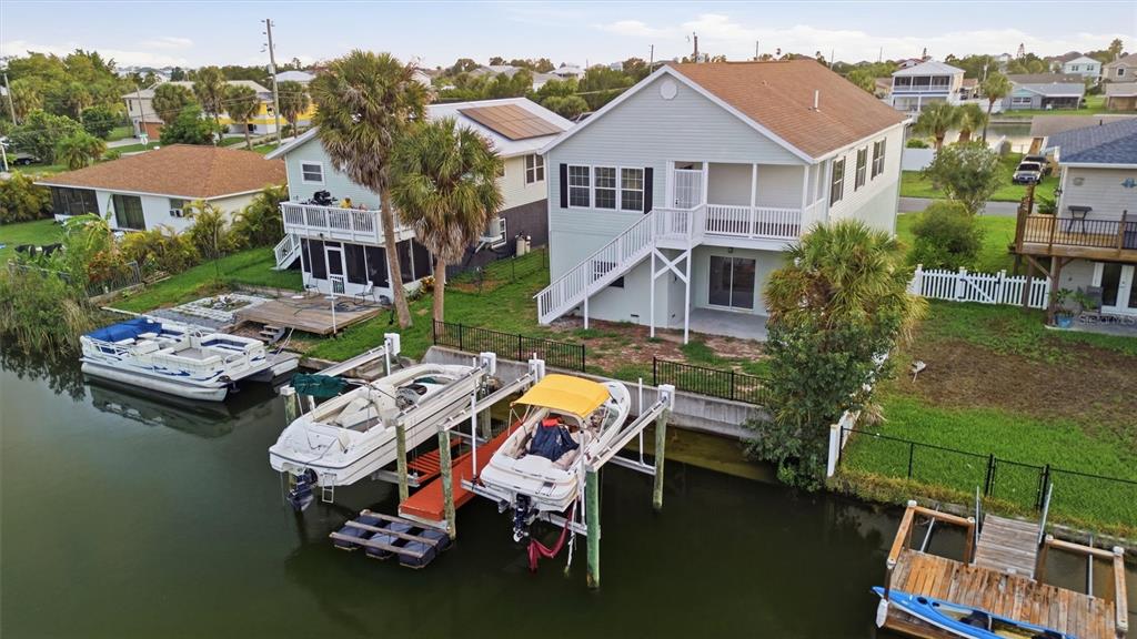 An aerial view shows waterfront houses with boat lifts and docks along a canal — 3316 HOLLY SPRINGS DRIVE, HERNANDO BEACH, FL