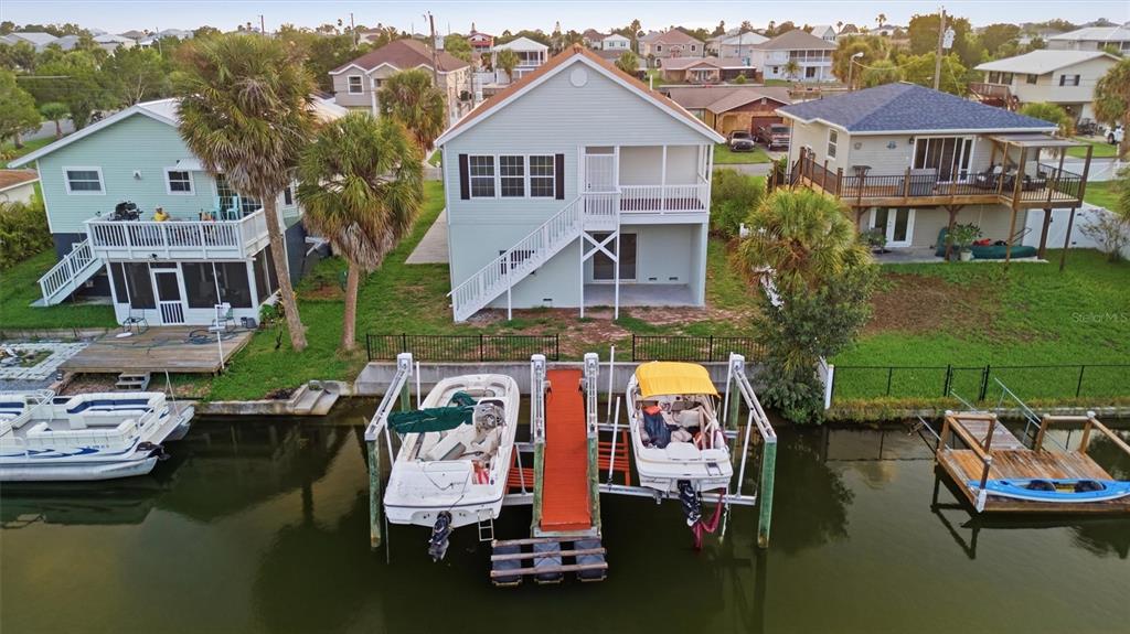 An aerial view shows a waterfront house with a boat lift and two docked boats — 3316 HOLLY SPRINGS DRIVE, HERNANDO BEACH, FL