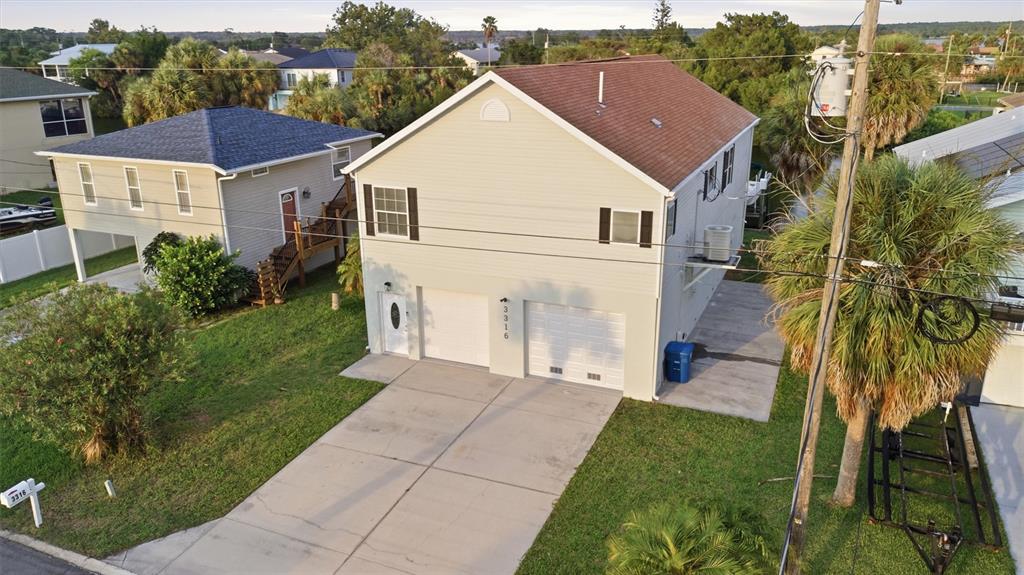An elevated two-story house with a two-car garage and a driveway sits on a lawn — 3316 HOLLY SPRINGS DRIVE, HERNANDO BEACH, FL