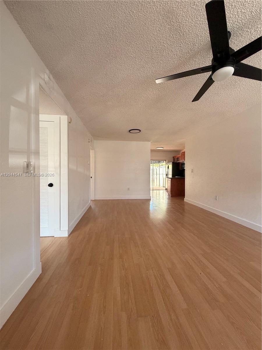 A living room with light wood-look flooring, white walls, and a black ceiling fan — 7000 NW 173rd Dr # 1805, Hialeah FL 33015, HIALEAH, FL