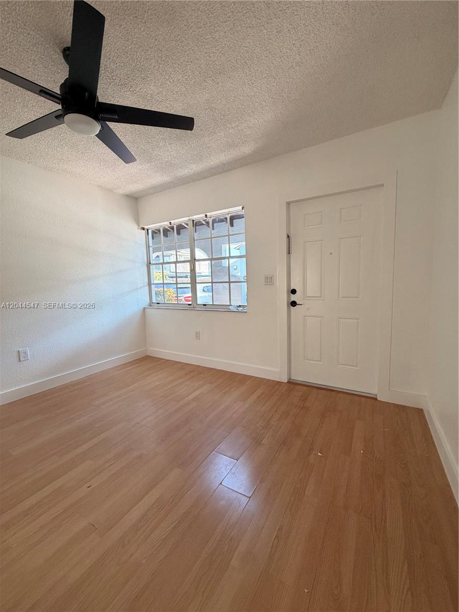 This living area features light wood-look flooring, white walls, and a black ceiling fan — 7000 NW 173rd Dr # 1805, Hialeah FL 33015, HIALEAH, FL
