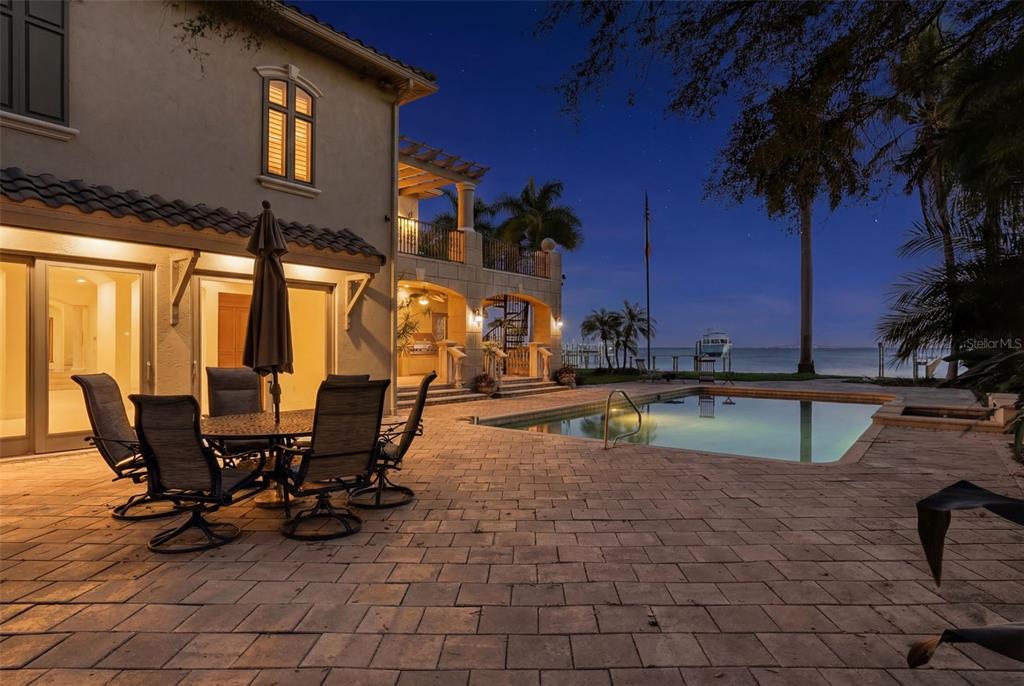 A patio with outdoor furniture and a swimming pool overlooks a waterfront view at dusk — 6755 30TH STREET S, ST PETERSBURG, FL