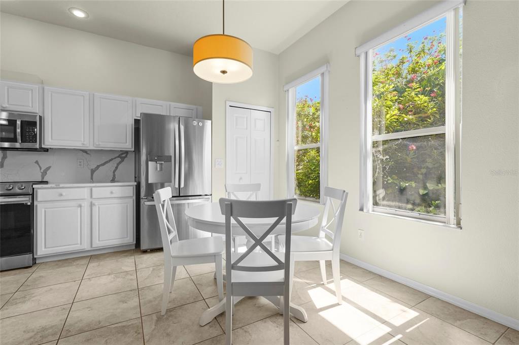 A kitchen with white cabinets, stainless steel appliances, a dining table, and two windows — 4510 50TH DRIVE W, BRADENTON, FL