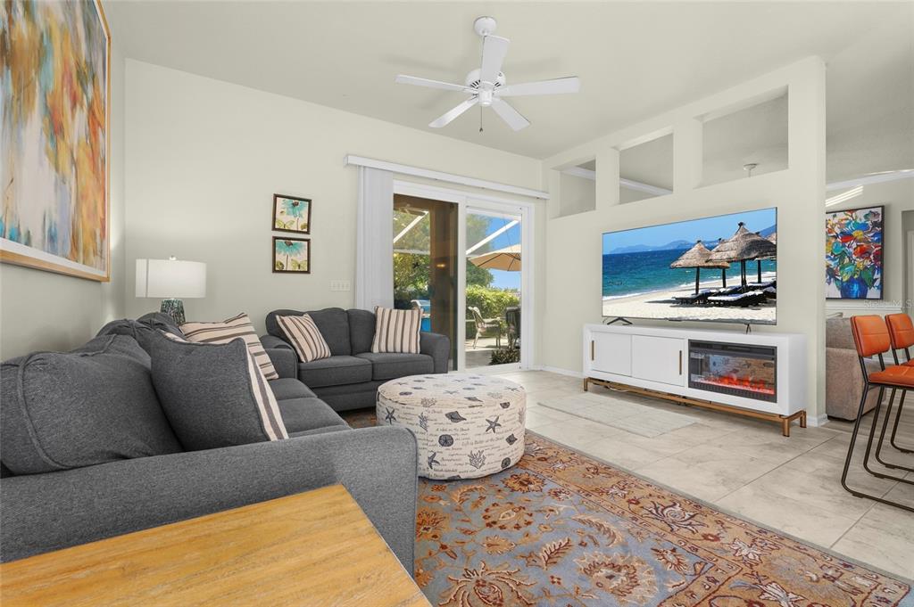 A living room features a grey sofa, patterned ottoman, area rug, and a media console — 4510 50TH DRIVE W, BRADENTON, FL