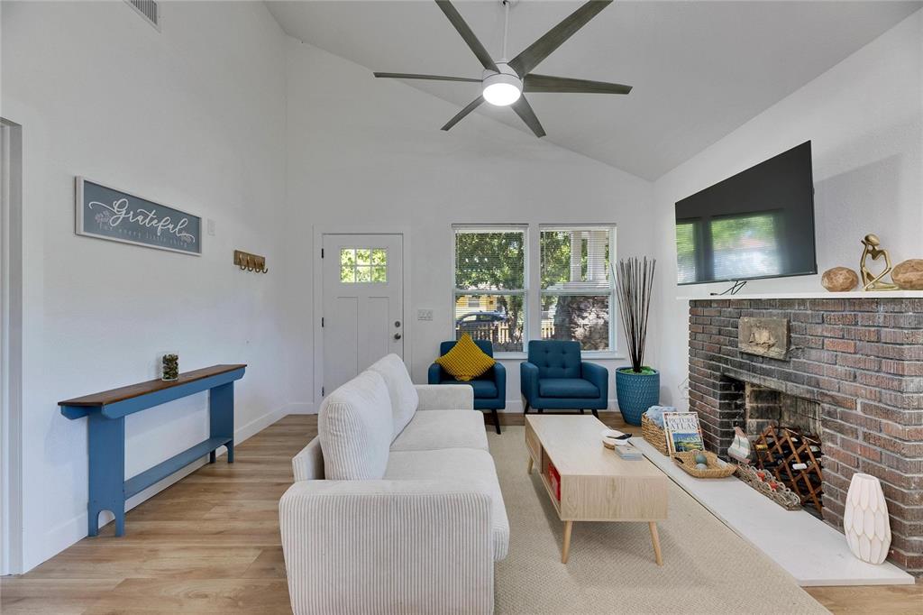 A living room features a vaulted ceiling, white walls, a brick fireplace, and wood flooring — 1021 E 25TH AVENUE, TAMPA, FL