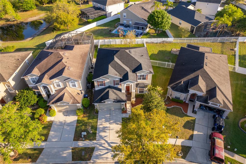 An aerial view shows three suburban houses with driveways and backyards in a residential neighborhood — 2591 DOVER GLEN CIRCLE, ORLANDO, FL