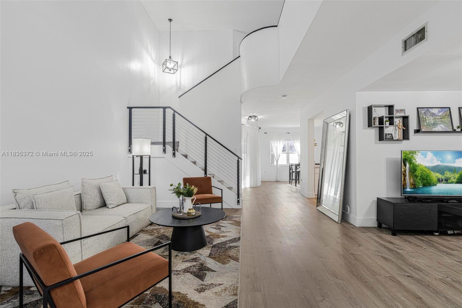 A modern living room features a staircase, light wood flooring, and a large floor mirror — 11532 SW 148th Path, Miami FL 33196, MIAMI, FL