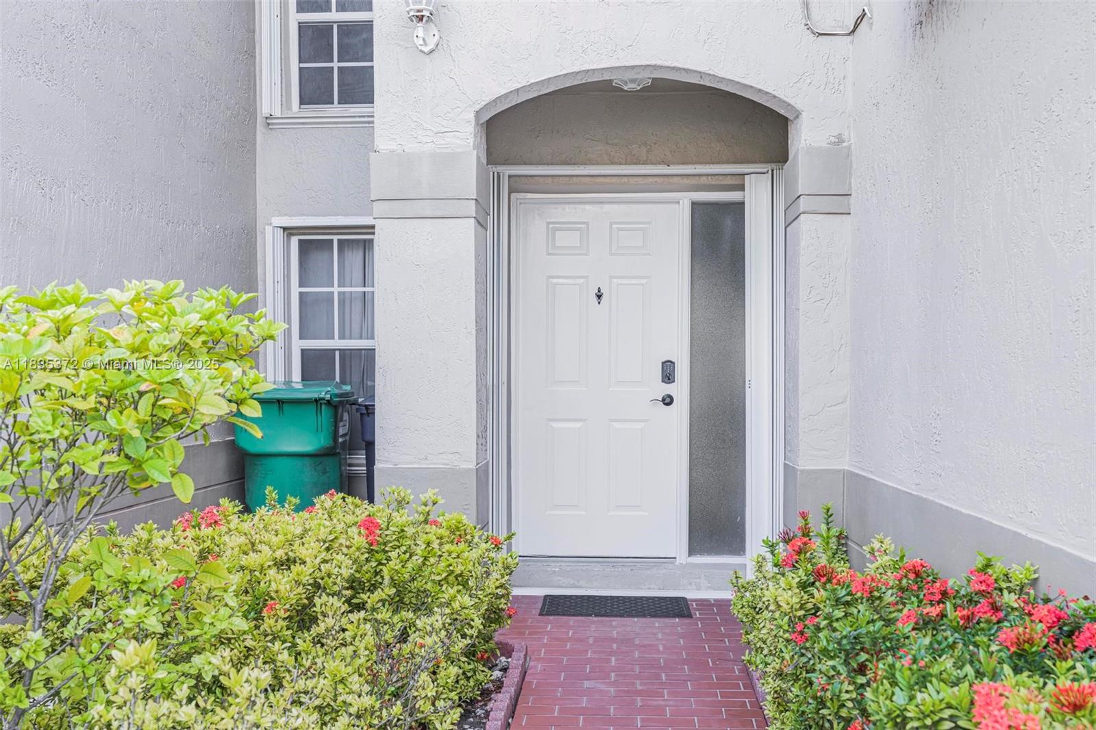 A white front door with a side window is set within an arched entryway — 11532 SW 148th Path, Miami FL 33196, MIAMI, FL