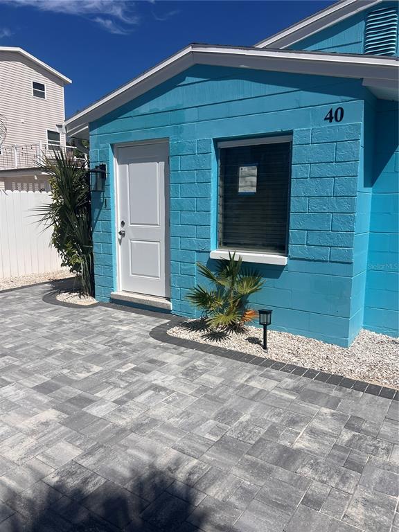 A bright blue concrete block building features a white door, window, and paved patio area — 40 82ND AVENUE S Unit `1, TREASURE ISLAND, FL