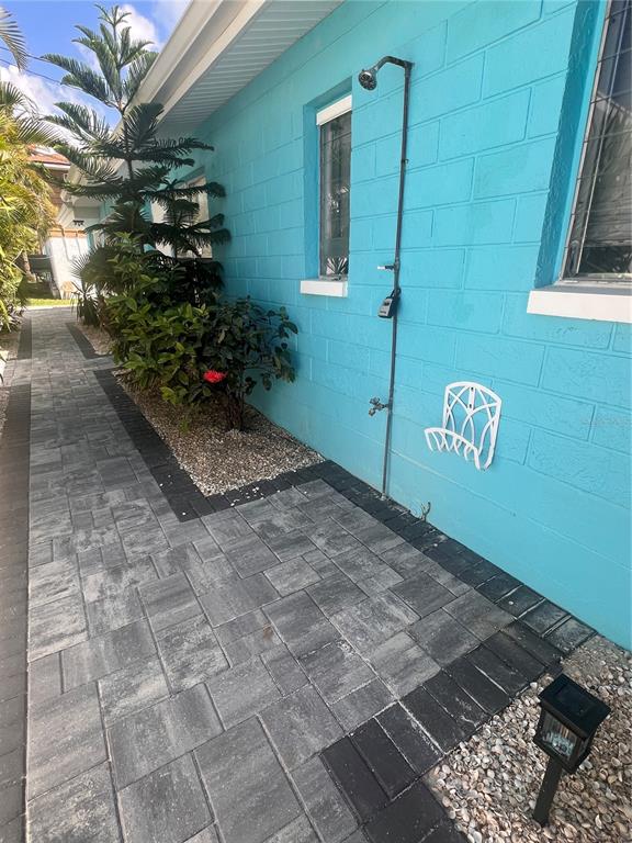 An outdoor shower is mounted on the exterior wall of a bright blue house — 40 82ND AVENUE S Unit `1, TREASURE ISLAND, FL
