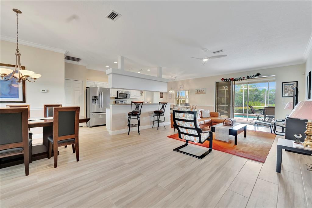 An open-concept living and dining area features tile flooring, a kitchen island, and sliding doors — 6738 PEACH TREE CREEK ROAD, BRADENTON, FL