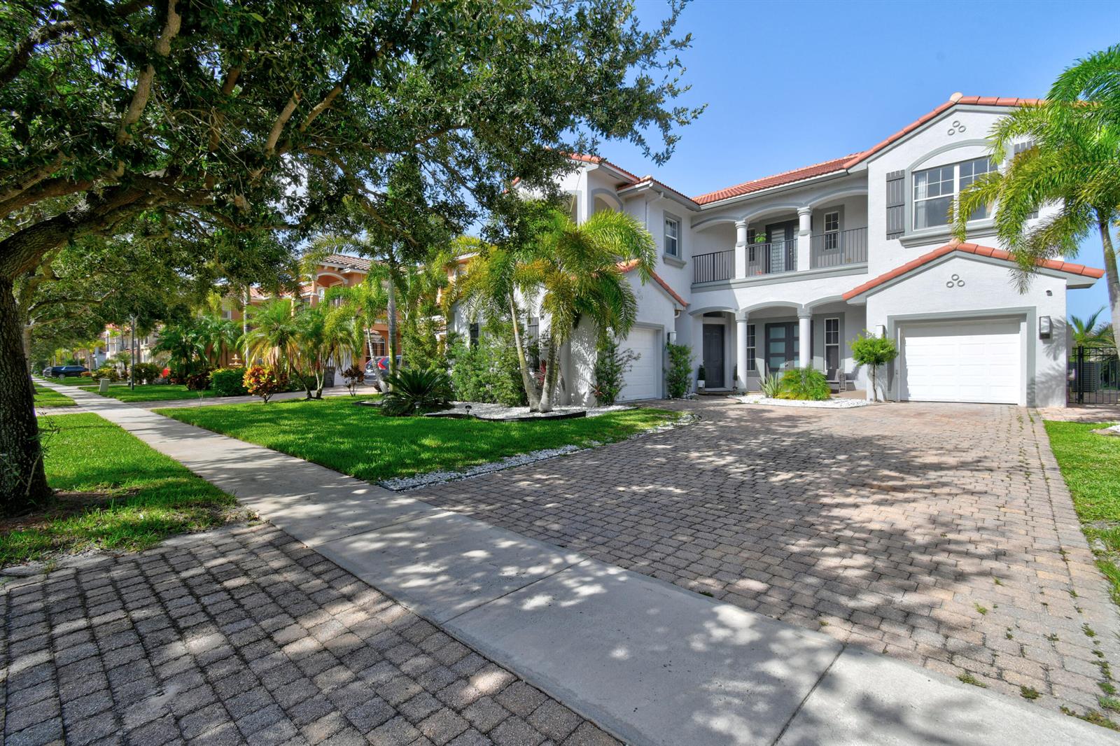 A two-story house with a tiled roof, paved driveway, and palm trees in the front yard — 700 Cresta Circle, West Palm Beach FL 33413, WEST PALM BEACH, FL