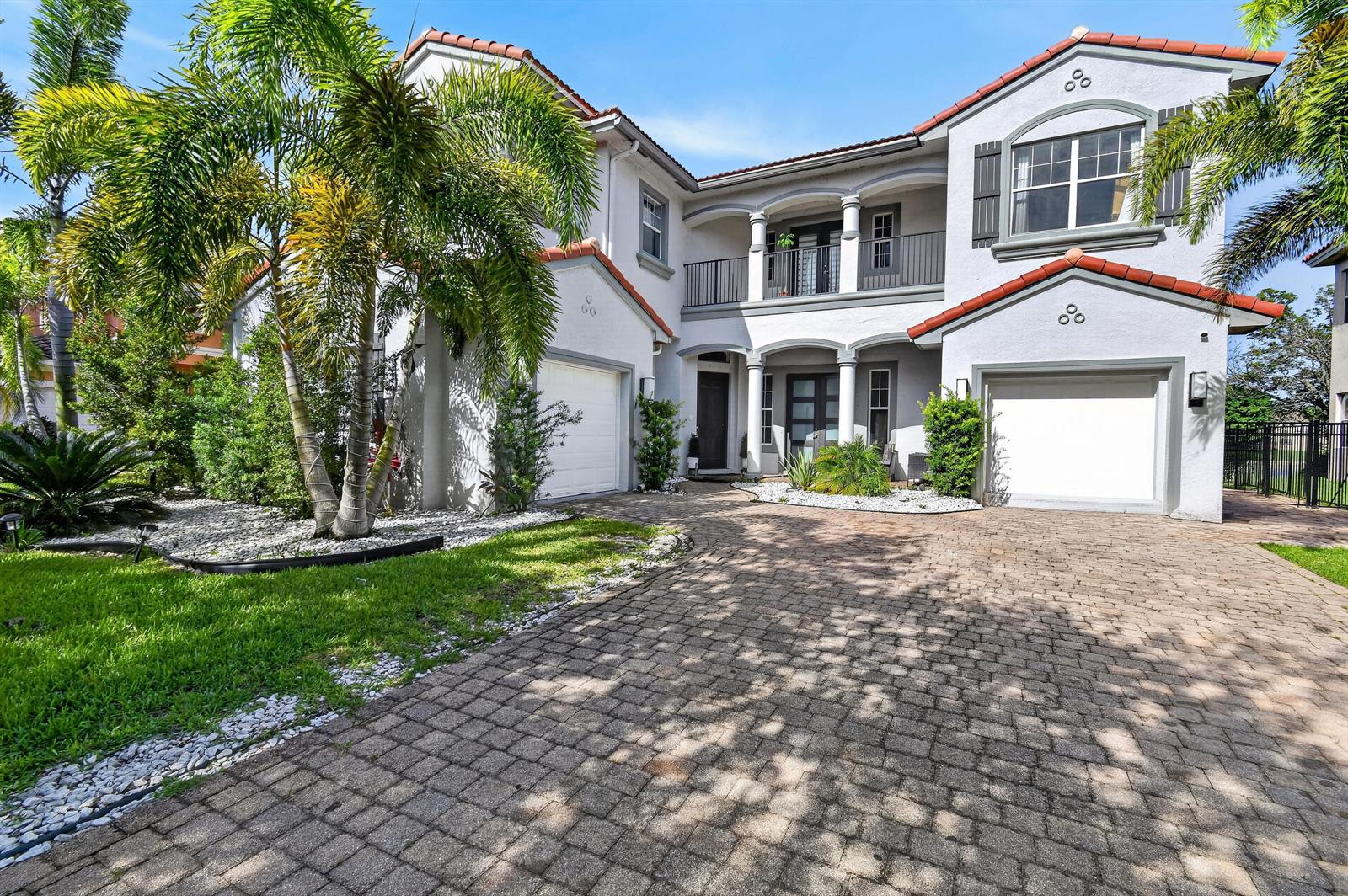 A two-story house with a paved driveway, two garage doors, and a second-floor balcony — 700 Cresta Circle, West Palm Beach FL 33413, WEST PALM BEACH, FL