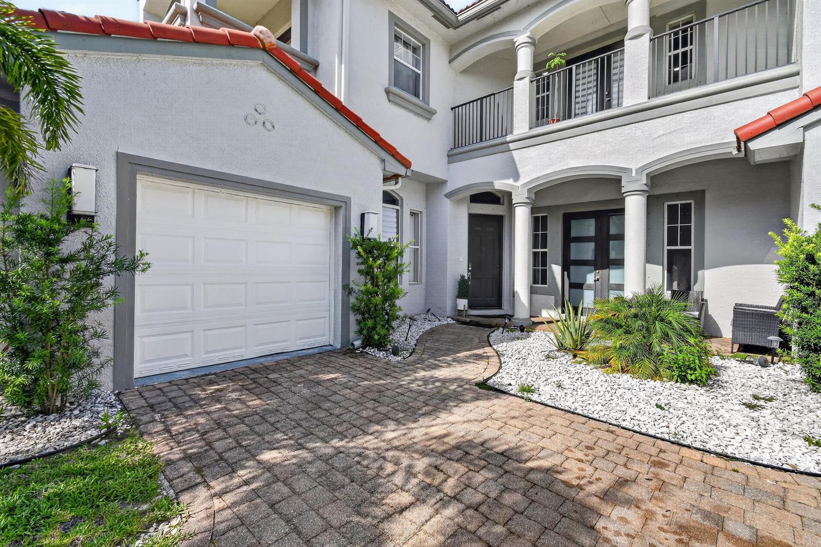 A two-story house exterior features a white stucco facade, a garage, and a paved driveway — 700 Cresta Circle, West Palm Beach FL 33413, WEST PALM BEACH, FL