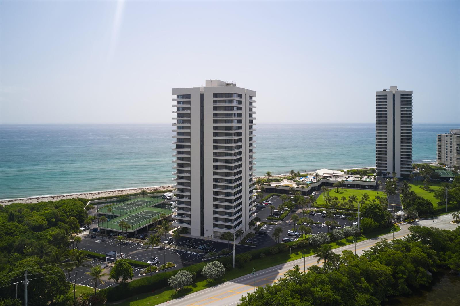 An aerial view shows two tall residential towers situated along a beach with tennis courts — 5550 N Ocean Drive # 9D, Singer Island FL 33404, SINGER ISLAND, FL