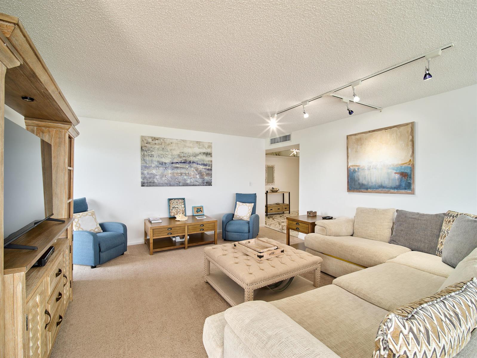 A living room features a beige sectional, two blue armchairs, and a tufted ottoman — 5550 N Ocean Drive # 9D, Singer Island FL 33404, SINGER ISLAND, FL