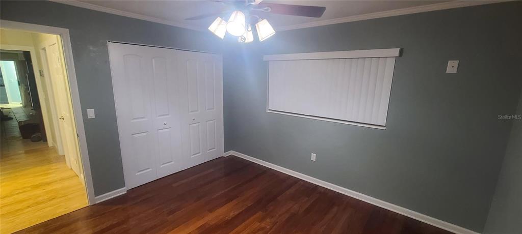 A bedroom features dark wood flooring, gray walls, a ceiling fan, and white closet doors — 2018 MARILYN AVENUE, WINTER HAVEN, FL