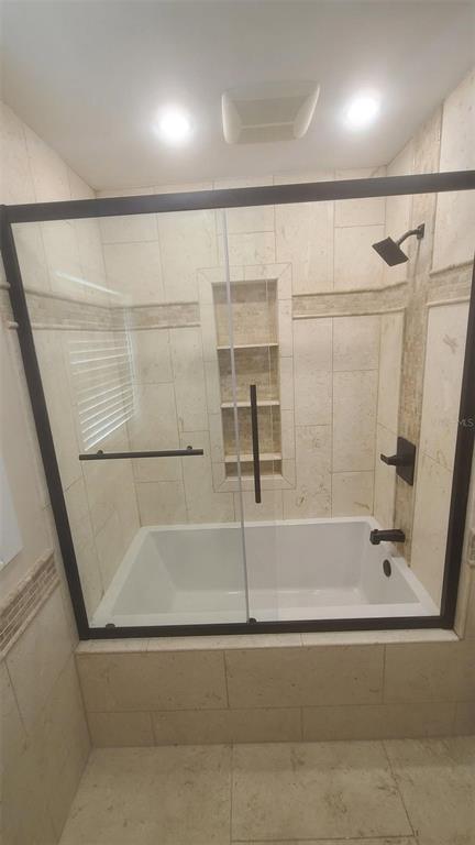 A bathroom features a white bathtub enclosed by a black-framed glass shower door and tile — 2018 MARILYN AVENUE, WINTER HAVEN, FL