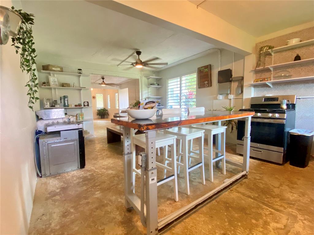 A kitchen features a central island with bar stools, open shelving, and a stainless stove — 4.8 CARR. 784 KM ROAD, CAGUAS, PR