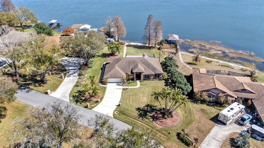 An aerial view shows a single-story house with a driveway and lawn near a lake — 122 W JULIANA WAY, AUBURNDALE, FL