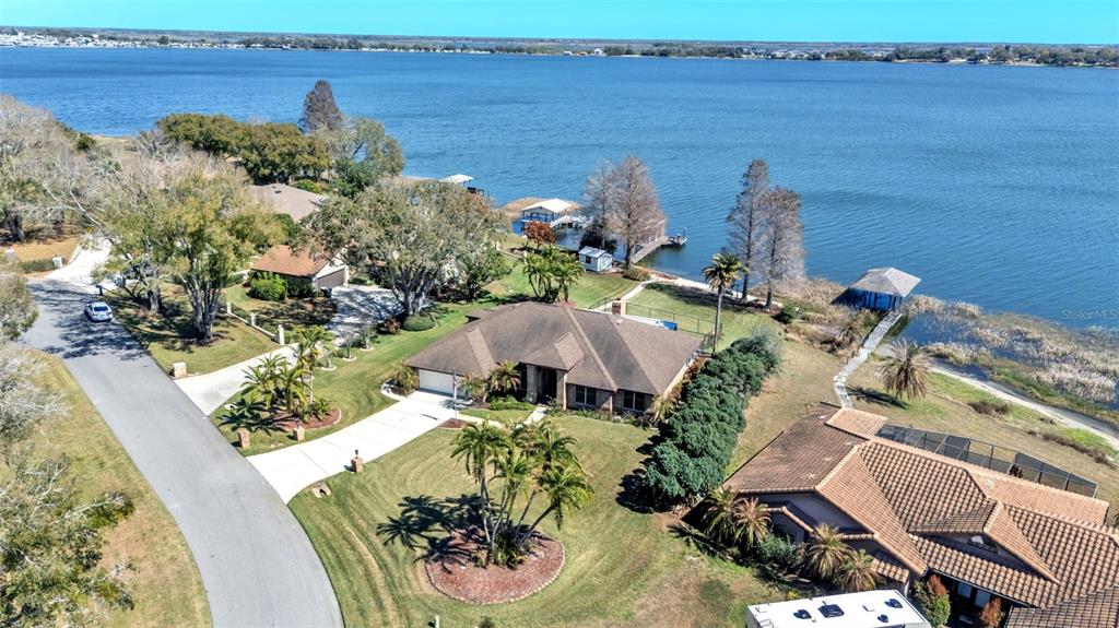 An aerial view shows a suburban house with a large lawn situated on a lakefront — 122 W JULIANA WAY, AUBURNDALE, FL