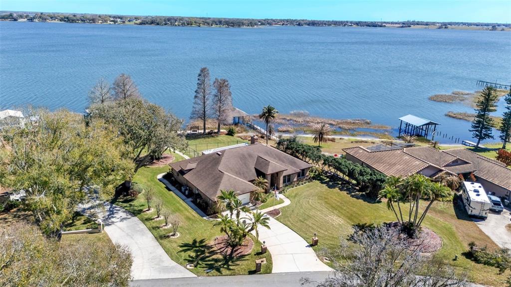 An aerial view shows a house with a brown roof and a large lakefront yard — 122 W JULIANA WAY, AUBURNDALE, FL