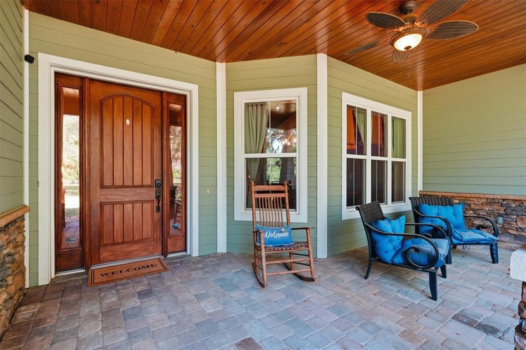 A covered front porch features a wooden door, a rocking chair, and two patio chairs — 12501 N US HIGHWAY 27, OCALA, FL