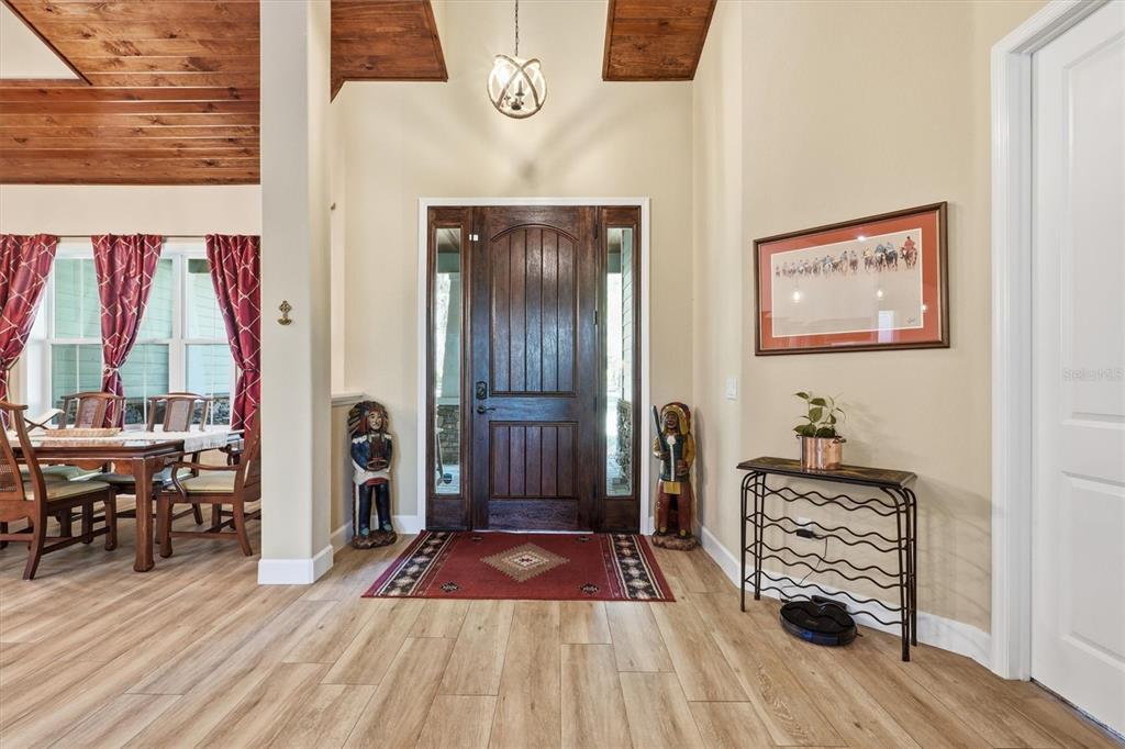 An entryway features a wood front door, light wood-look flooring, and two decorative carved figures — 12501 N US HIGHWAY 27, OCALA, FL