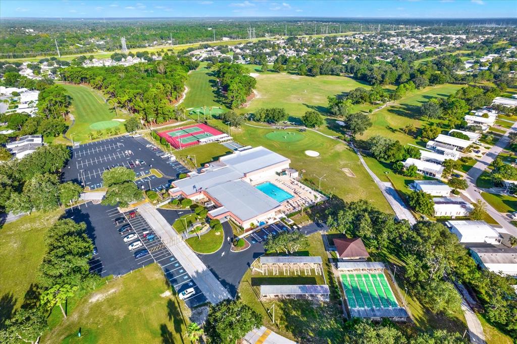 An aerial view shows a community clubhouse with a pool, tennis courts, and parking — 8431 MOONLIGHT AVENUE, BROOKSVILLE, FL