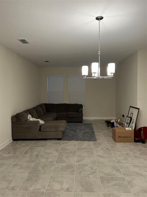 A living room features a large gray sectional sofa, tile flooring, and a modern chandelier — 14186 TITLE WAY, WINTER GARDEN, FL