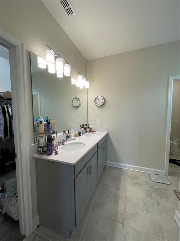 A bathroom features a double vanity with a white countertop, gray cabinets, and a large mirror — 14186 TITLE WAY, WINTER GARDEN, FL