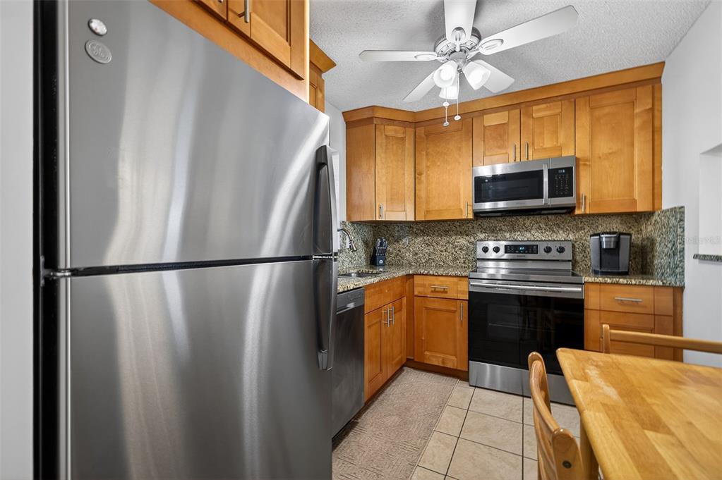A kitchen features stainless steel appliances, wood cabinets, and granite countertops — 7625 SUN ISLAND DRIVE S UNIT 207, SOUTH PASADENA, FL