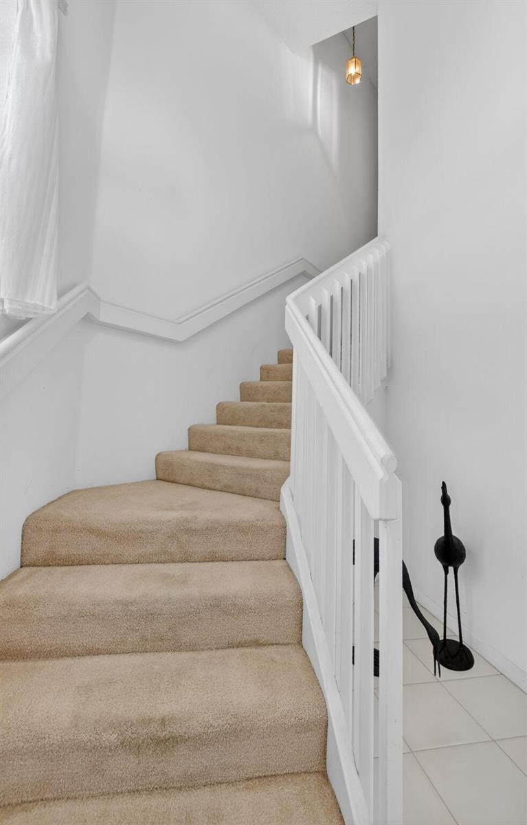 A carpeted staircase with a white wooden railing leads to an upper level — 5366 Venetia Court, Boynton Beach FL 33437, BOYNTON BEACH, FL
