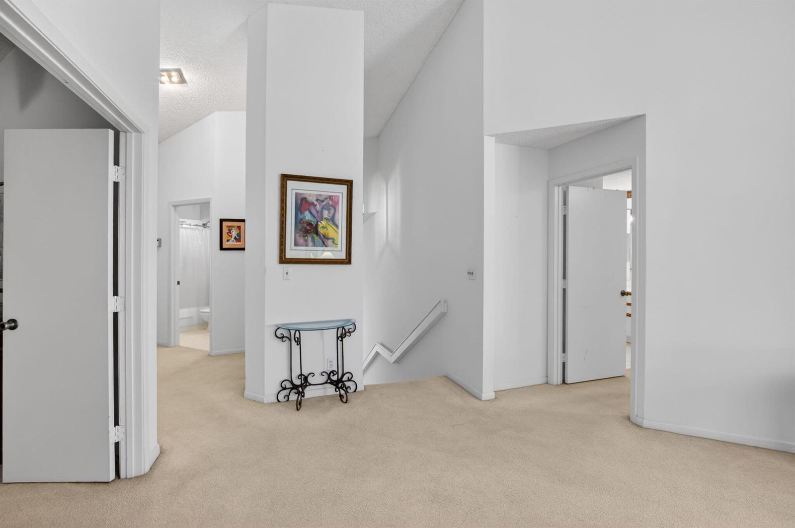 A carpeted hallway features white walls, a central pillar with artwork, and several doorways — 5366 Venetia Court, Boynton Beach FL 33437, BOYNTON BEACH, FL