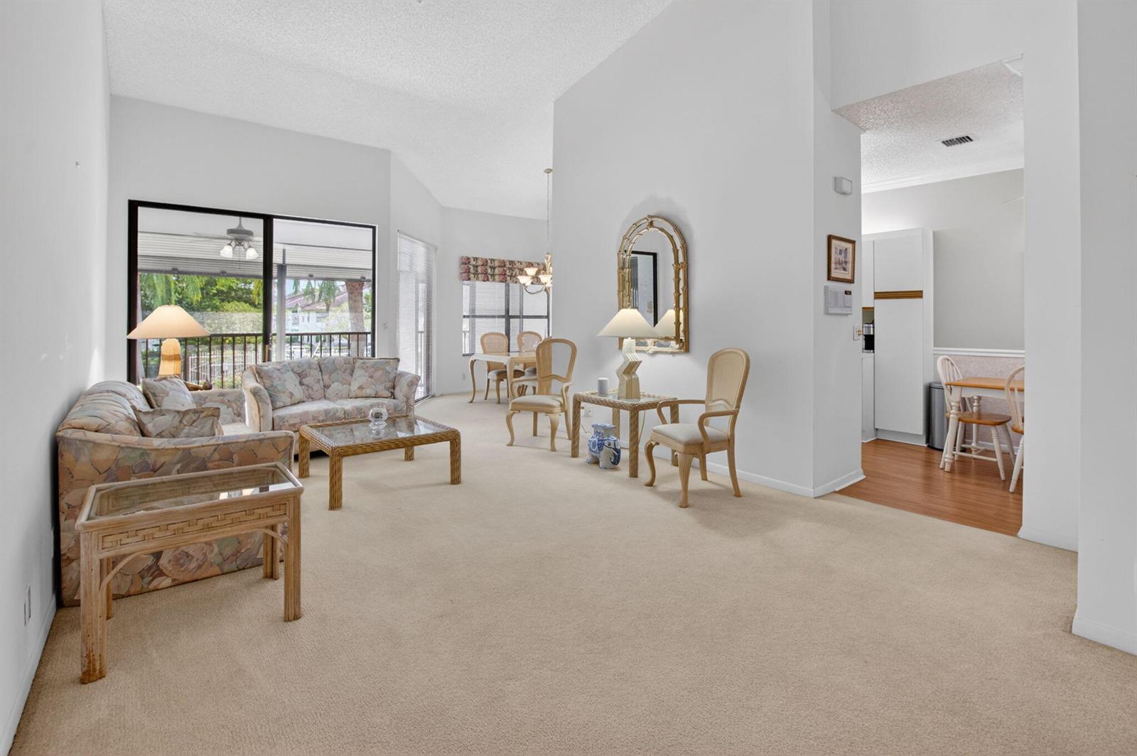 A living room with beige carpet, white walls, and a view of a covered patio — 5366 Venetia Court, Boynton Beach FL 33437, BOYNTON BEACH, FL
