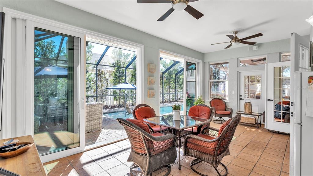 A sunroom with tile floors, wicker furniture, and sliding glass doors overlooking a pool area — 2409 JENNA LN, LAKELAND, FL