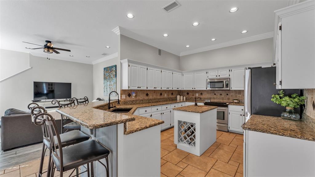 A living room with a sofa and rug opens into a dining area with columns — 2409 JENNA LN, LAKELAND, FL