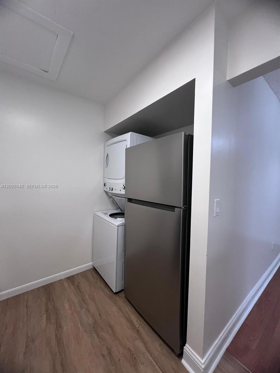 A stainless steel refrigerator stands next to a stacked washer and dryer unit — 2570 W 67th Pl # 2, Hialeah FL 33016, HIALEAH, FL