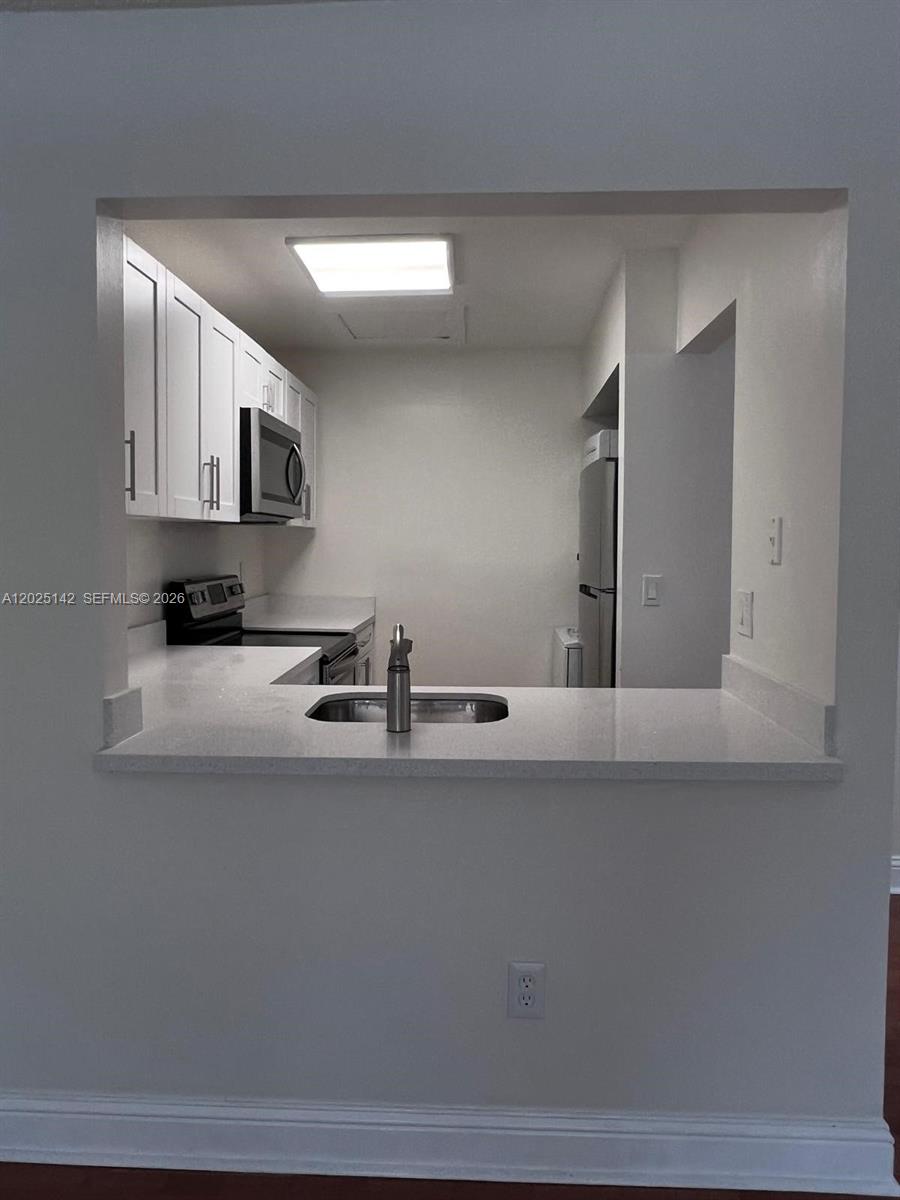 A kitchen with white cabinets, stainless steel appliances, and a pass-through counter with a sink — 2570 W 67th Pl # 2, Hialeah FL 33016, HIALEAH, FL