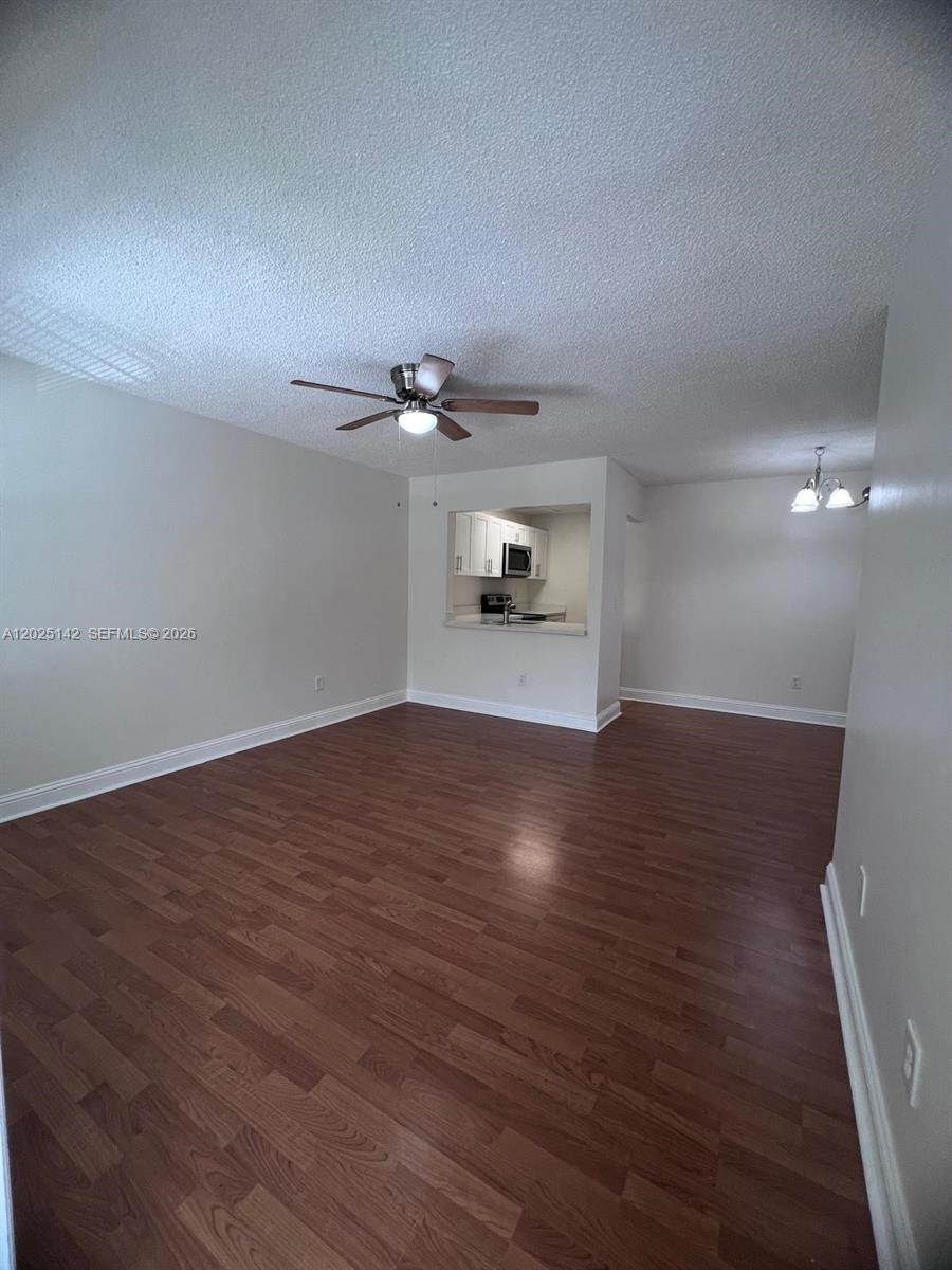 This living room features wood-look flooring, a ceiling fan, and an open kitchen pass-through — 2570 W 67th Pl # 2, Hialeah FL 33016, HIALEAH, FL