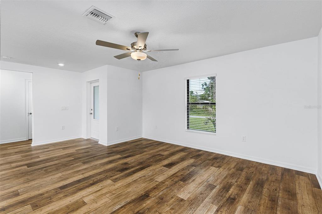 An empty room with white walls, wood-look flooring, a ceiling fan, and a single window — 6007 GILLOT BOULEVARD, PORT CHARLOTTE, FL
